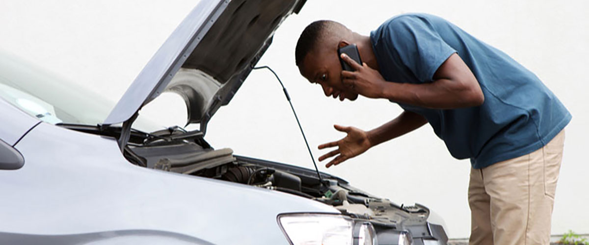 man looking at a car that needs repairs