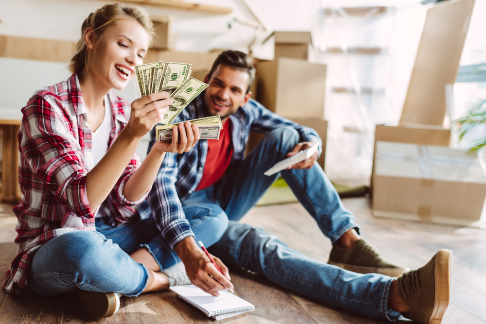 Happy young couple with calculator counting cash.
