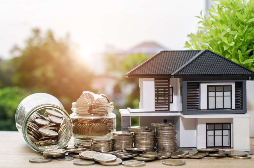 Model house with overflowing jar of coins.