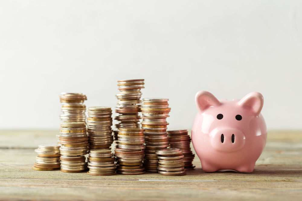 Piggy bank with coins on wooden table.