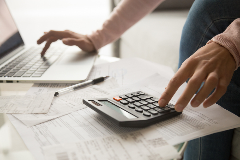 Close up of young women using calculator and laptop
