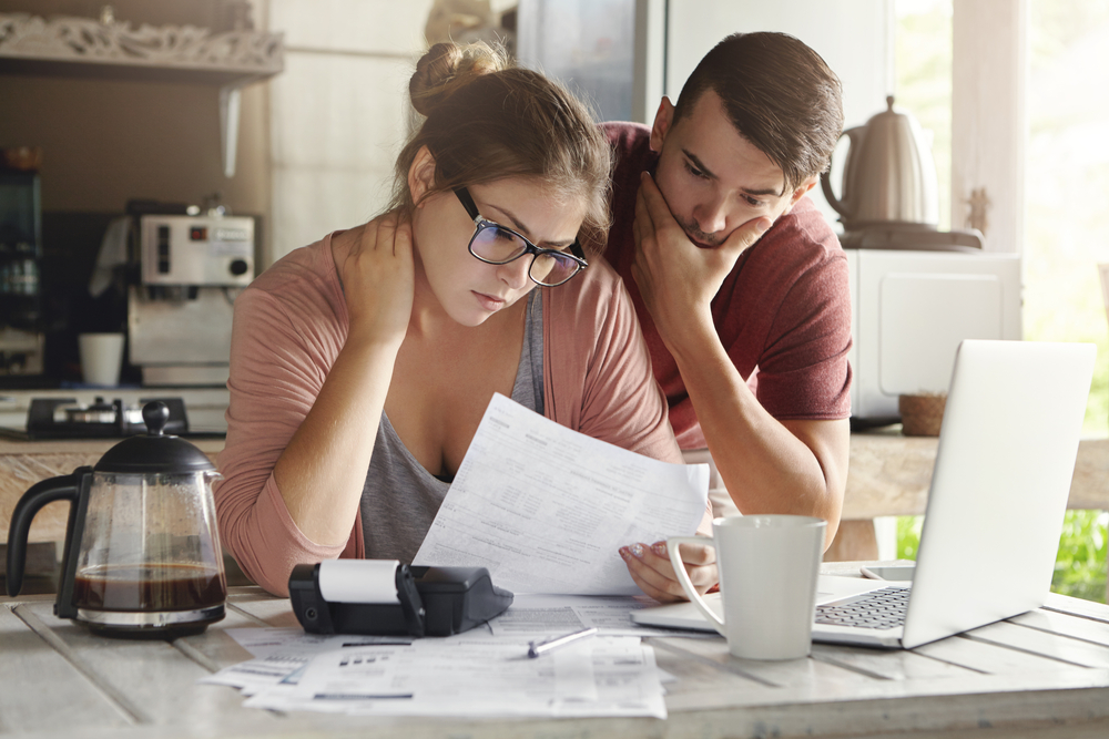 Young woman in glasses and brunette man concerned about bills.