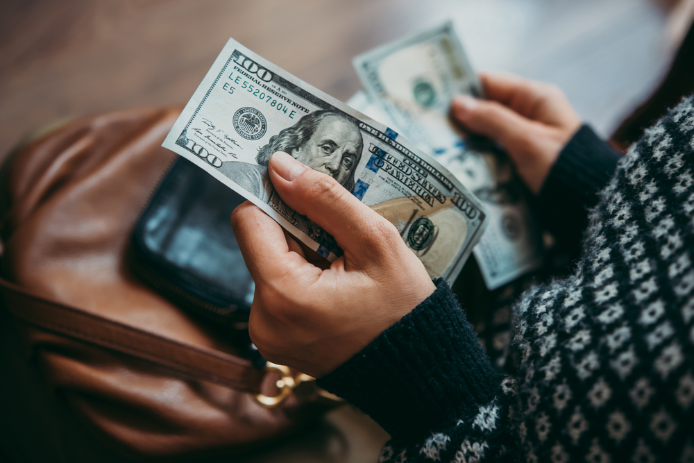 Over-the-shoulder shot of a woman’s hands counting cash.