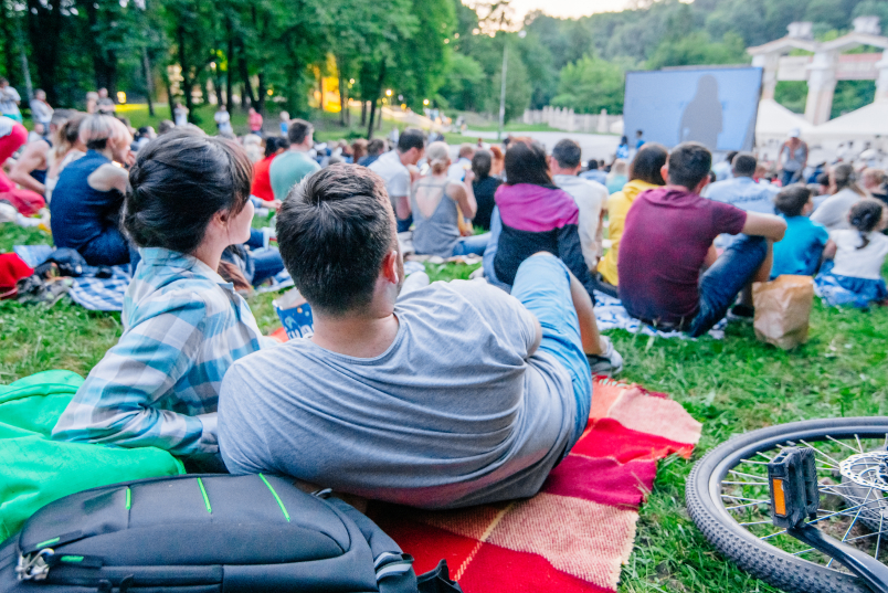 People watching movie in open air cinema in city park