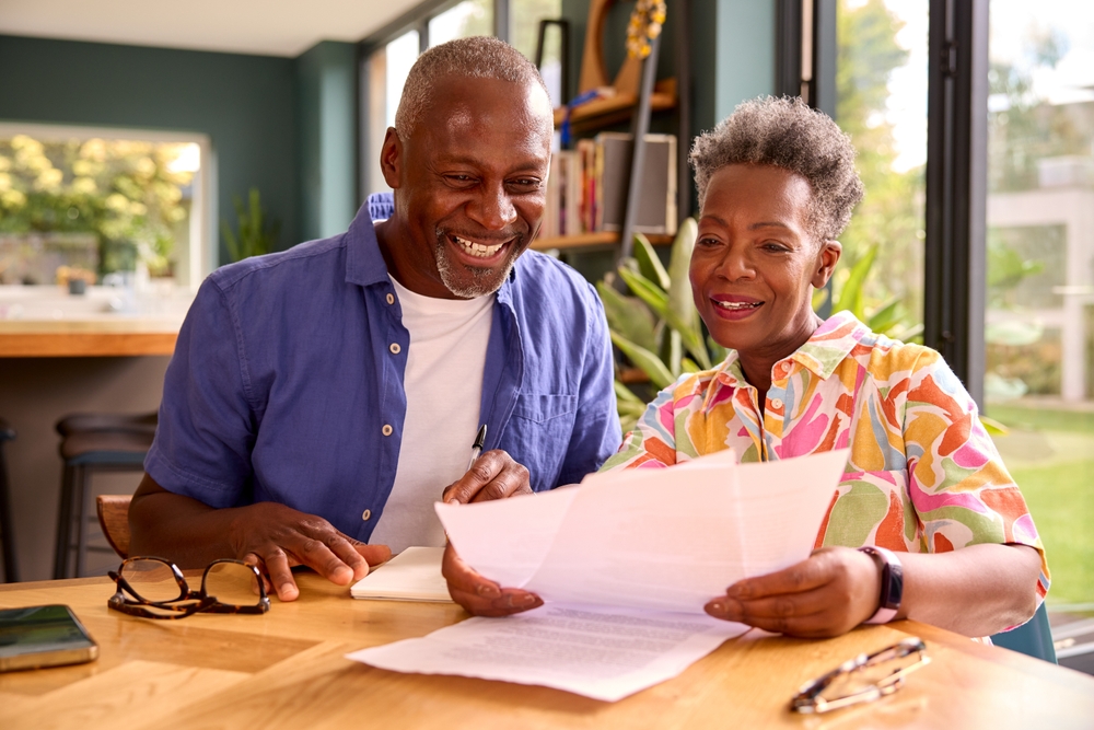 Smiling senior couple sitting at table reviewing finances.