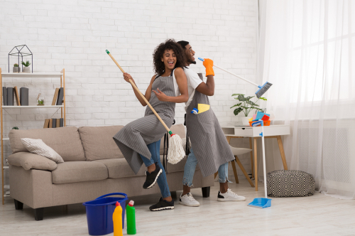 black man and woman having fun during house cleaning, playing with mop and broom