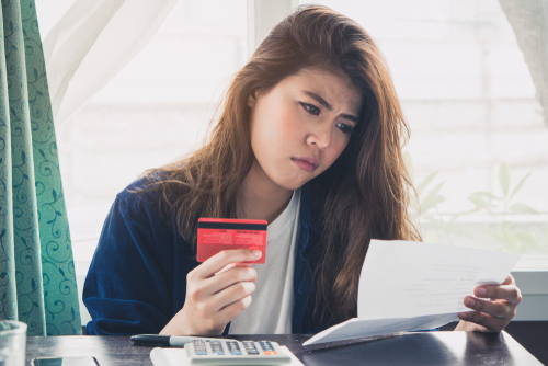 stressed young asian woman trying to find money to pay credit card debt