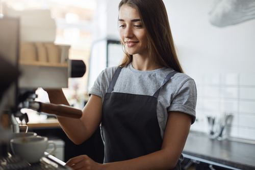 Woman uses espresso machine at a coffee shop