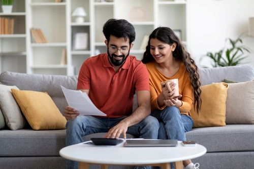 couple uses calculator sitting on couch