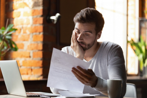 man frustrated while looking at bills