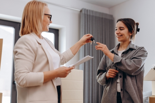woman handing another woman house keys