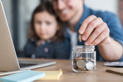 Father and daughter put change in a jar