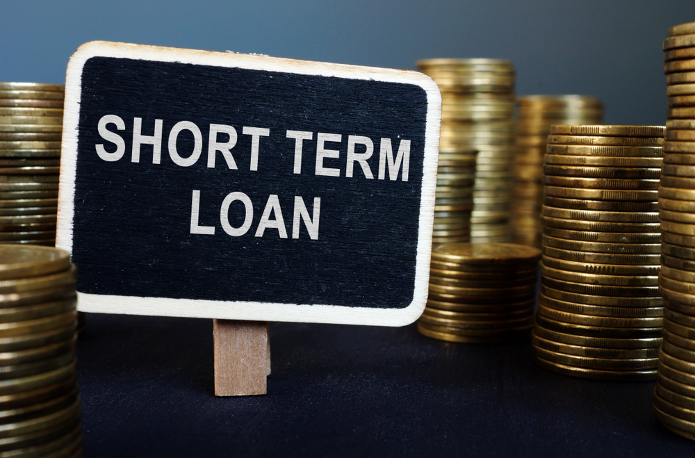 stacks of gold coins with a sign that says "short term loan"