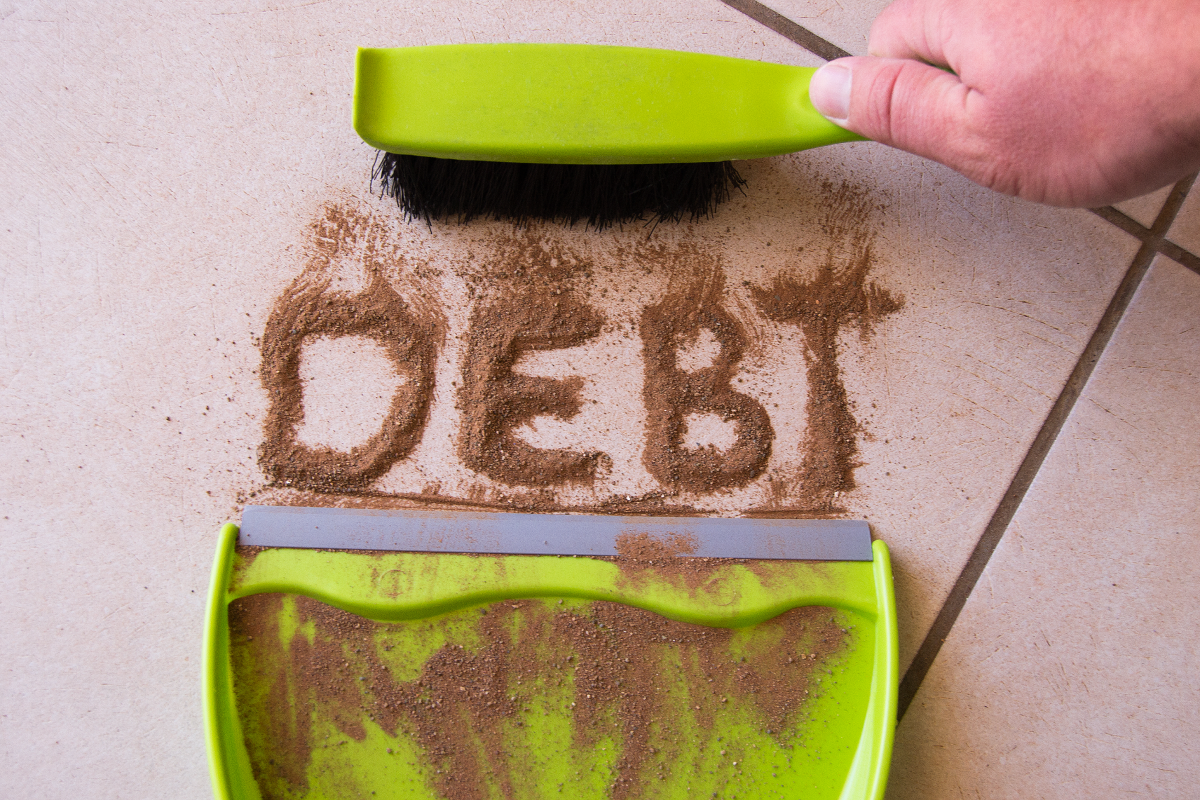 "debt" written in dirt being cleaned
