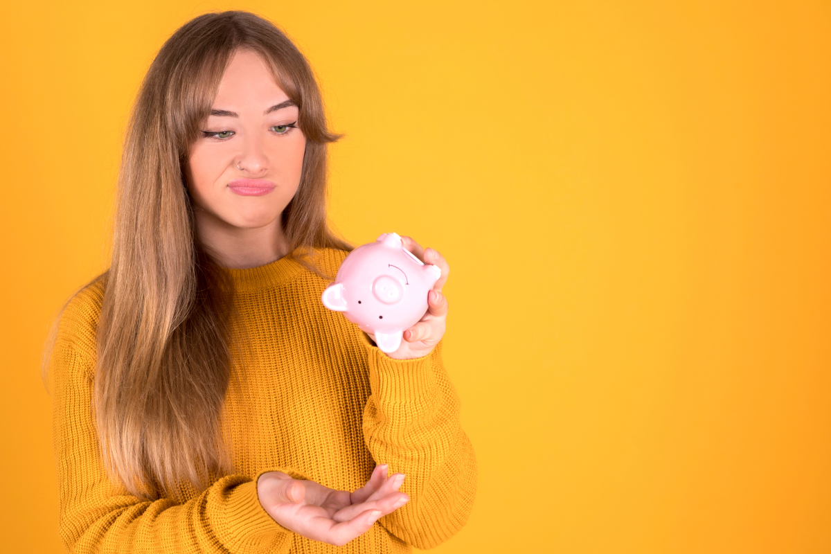 woman scowls at empty piggy bank