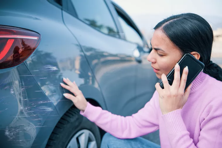 woman looking at damaged car