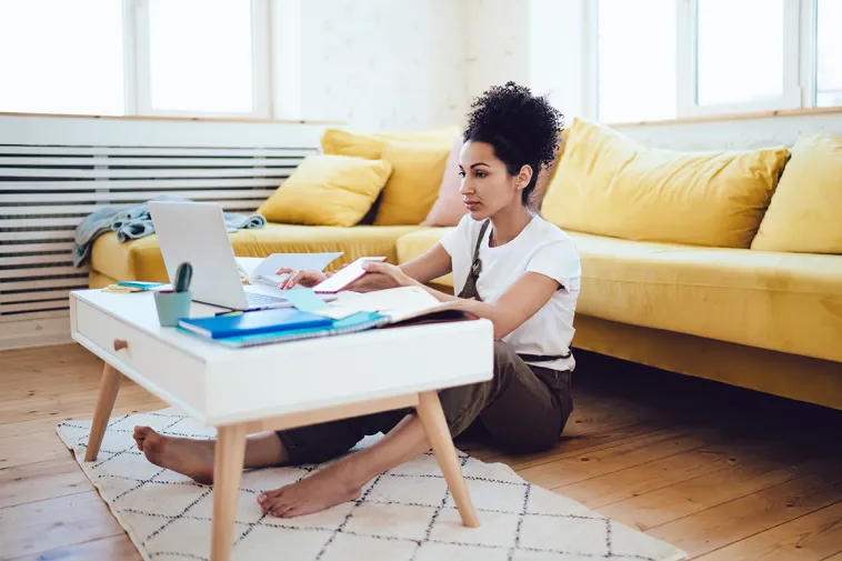 Woman at coffee table using laptop and phone