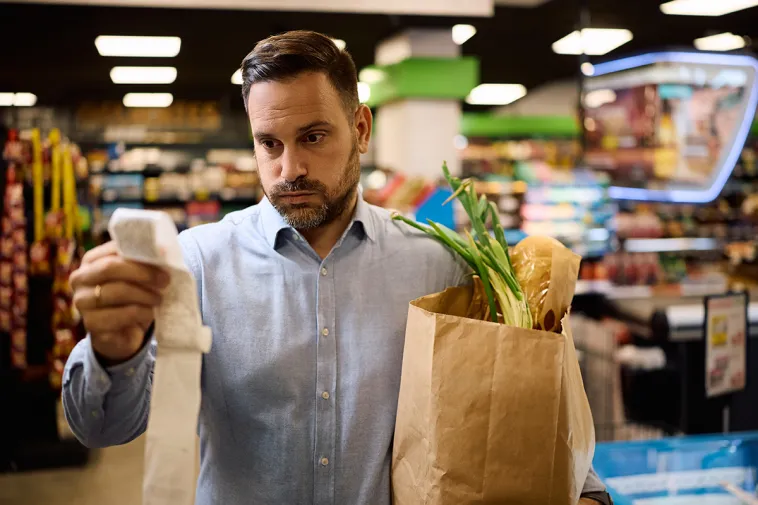 Cost of living increases - Man looking at shopping receipt