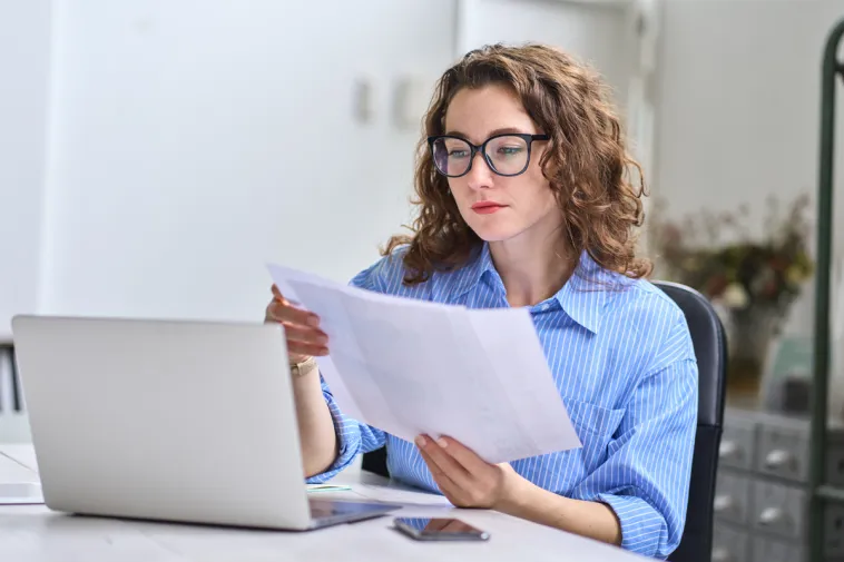 A woman reviews her finances at home, considering using an Advance America line of credit to consolidate debt.