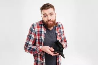 Young bearded man holding an empty wallet and shrugging