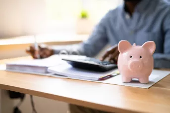 man using calculator with piggy bank